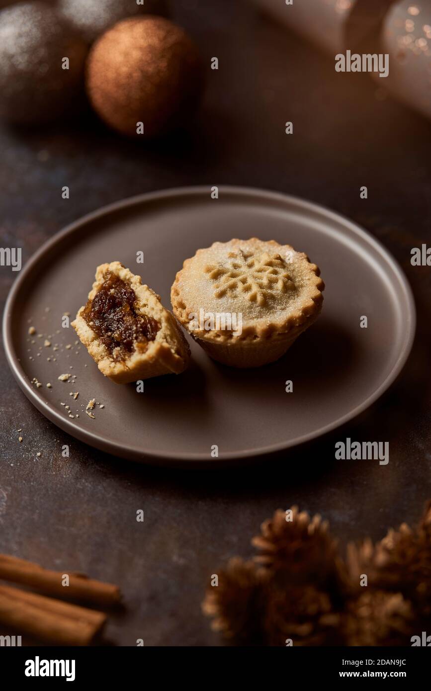 Mince pies on a grey plate surrounded by Christmas decorations Stock Photo