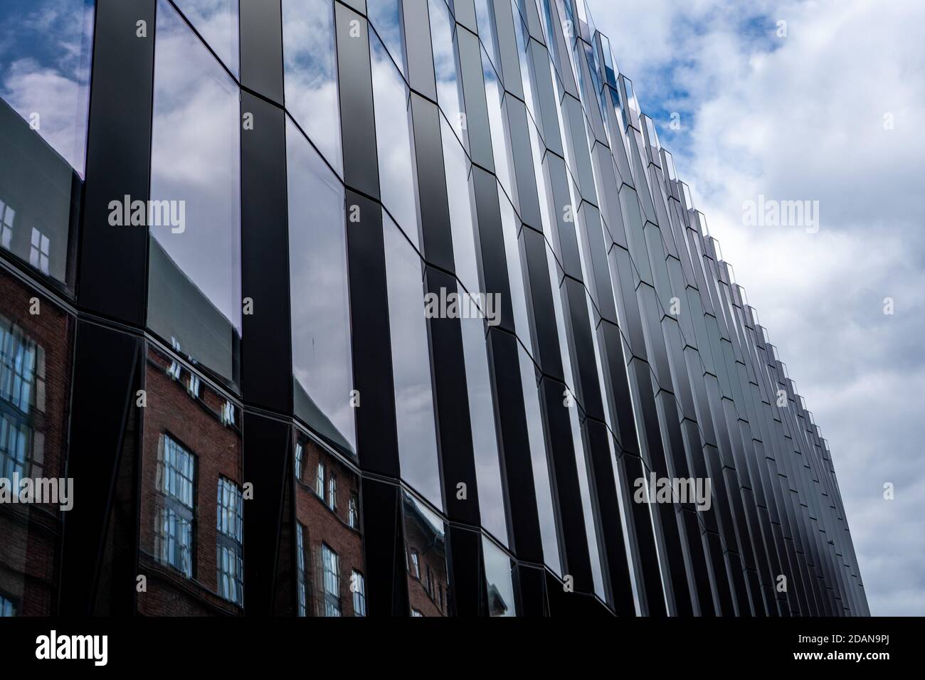 modern office building with sky and clouds reflecting in the windows ...