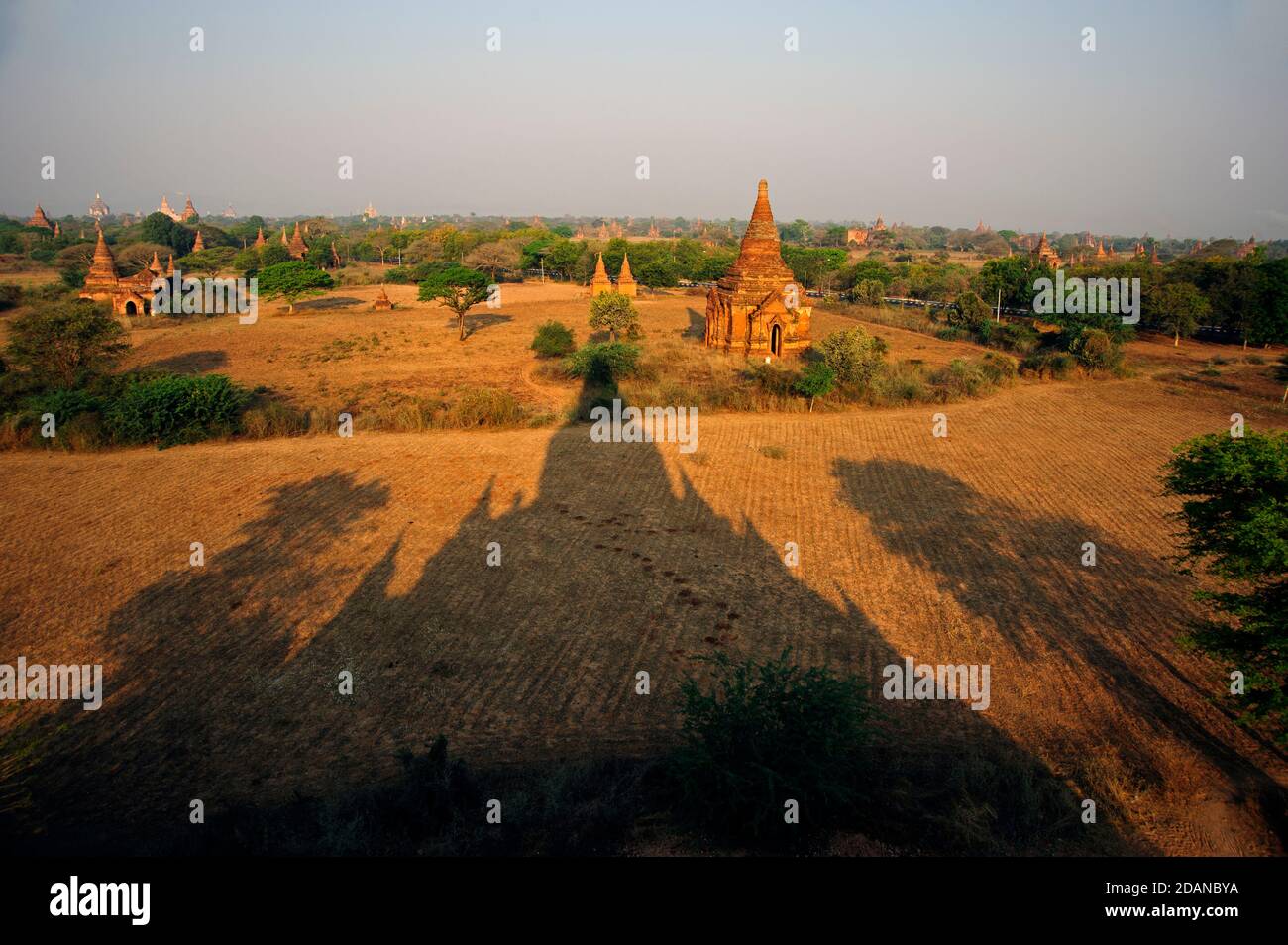 The long dark distinct temple shadow stretches out towards the temple on the dusty Bagan palin Bagan Myanmar Stock Photo
