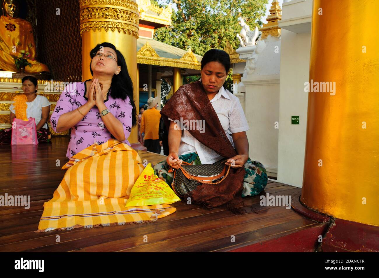 Two Burmese women crossed legged worship in deep prayer at the Shwedagon Pagoda in Yangon Myanmar Stock Photo