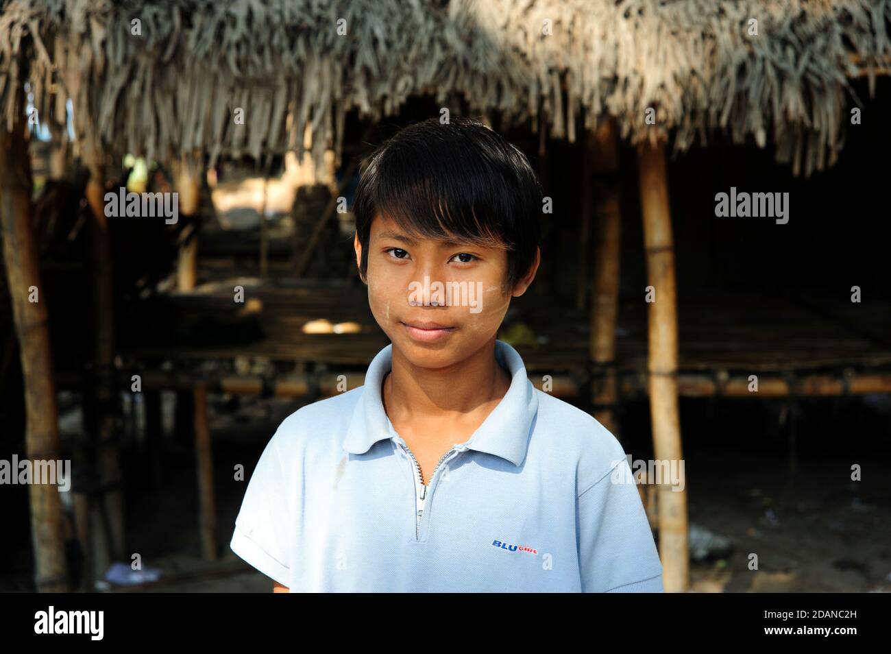 A smiling Burmese boy portrait outside his thatched village hut on Ngapali beach Myanmar Stock Photo