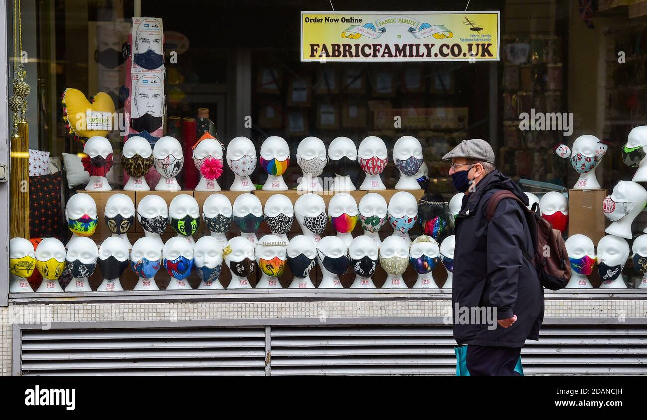 Brighton UK 14th November 2020 - A man wearing a face covering passes a closed shop selling masks in Brighton as the shopping area of the city remains quiet due to the latest Coronavirus COVID-19 lockdown restrictions in England : Credit Simon Dack / Alamy Live News Stock Photo