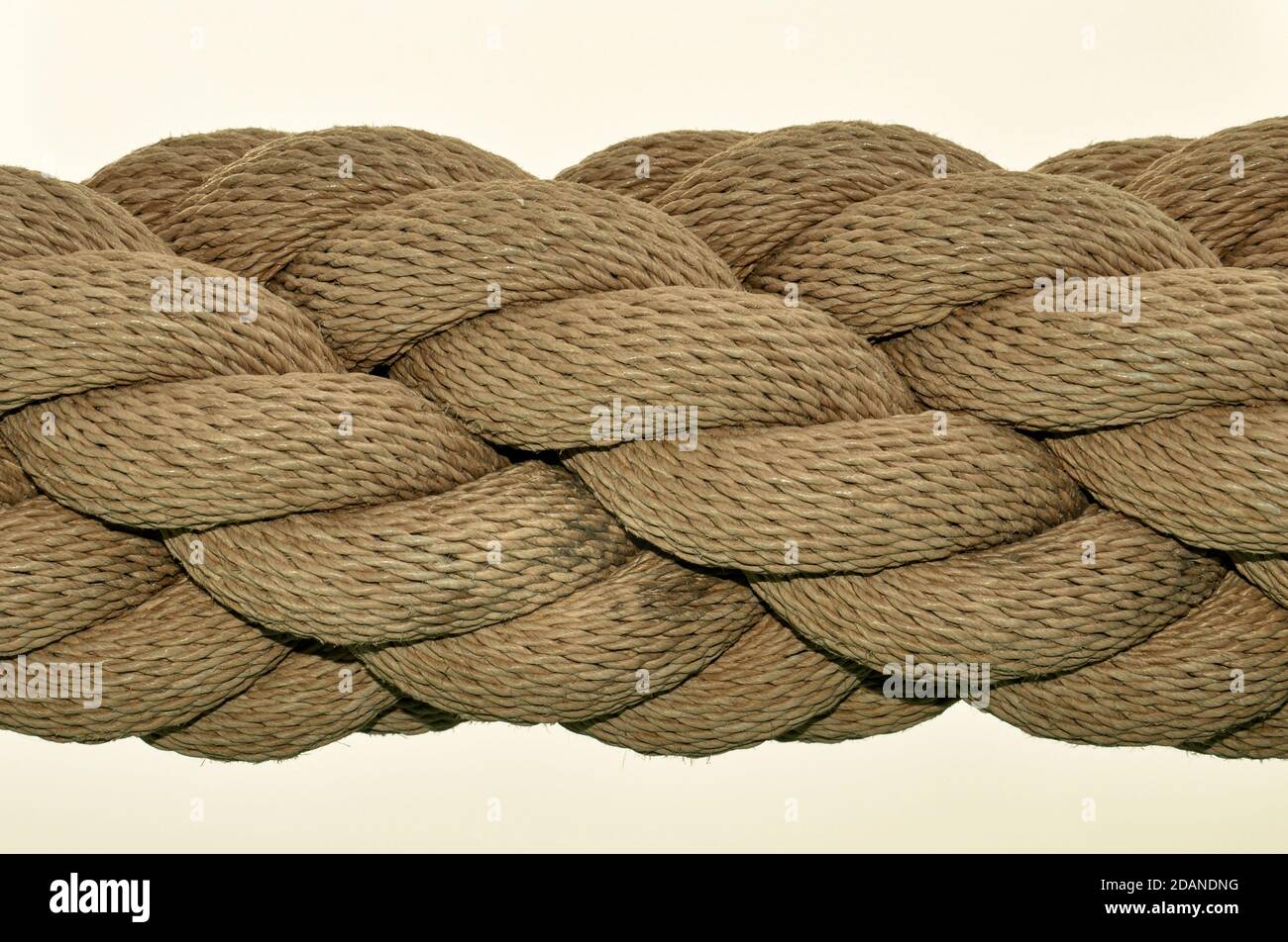 A black and white close up image of a thick industrial rope, with many rope lengths coiled together in a spiral. Stock Photo