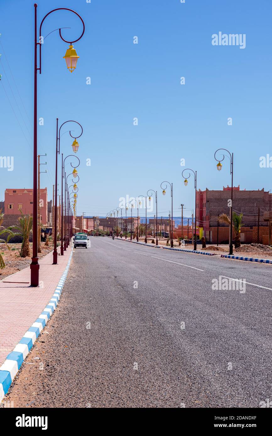 Wide angle shot of buildings, street lamps and road of the town of Tagonite in Draa Valley, Morocco Stock Photo