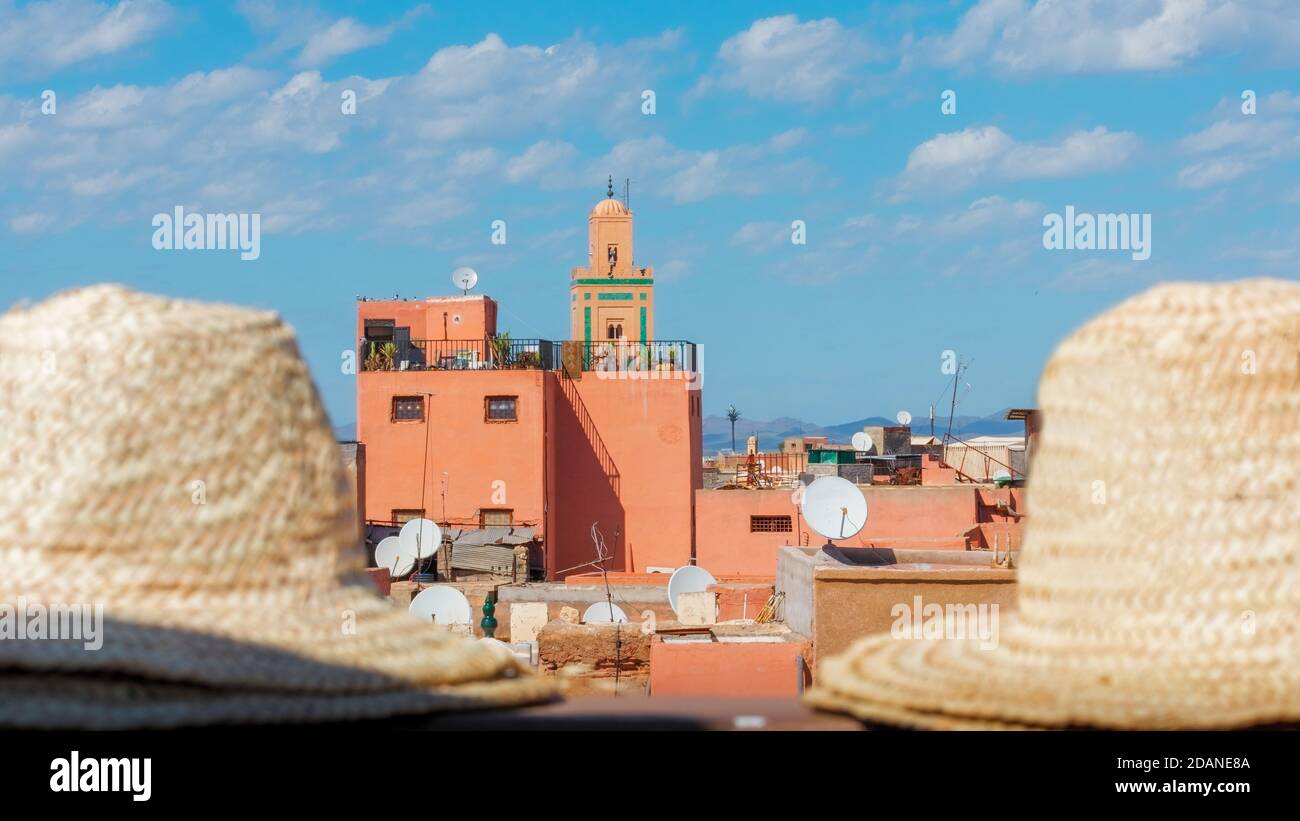 Typical colorful buildings of the Marrakesh medina on a sunny day with a blue sky and some clouds. Hats out of focus in the foreground. Travel concept Stock Photo