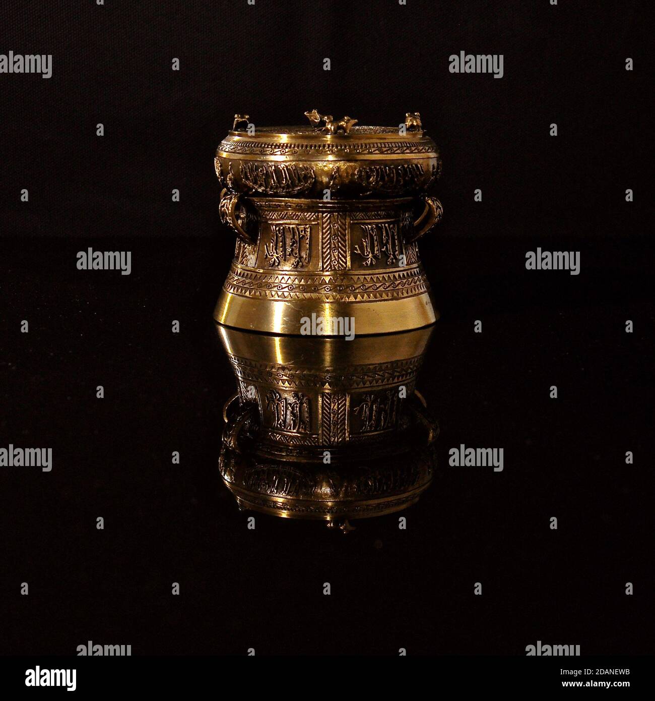 Ornate bronze ornament on a shiny black reflective surface, showing an inverted mirror image. Stock Photo