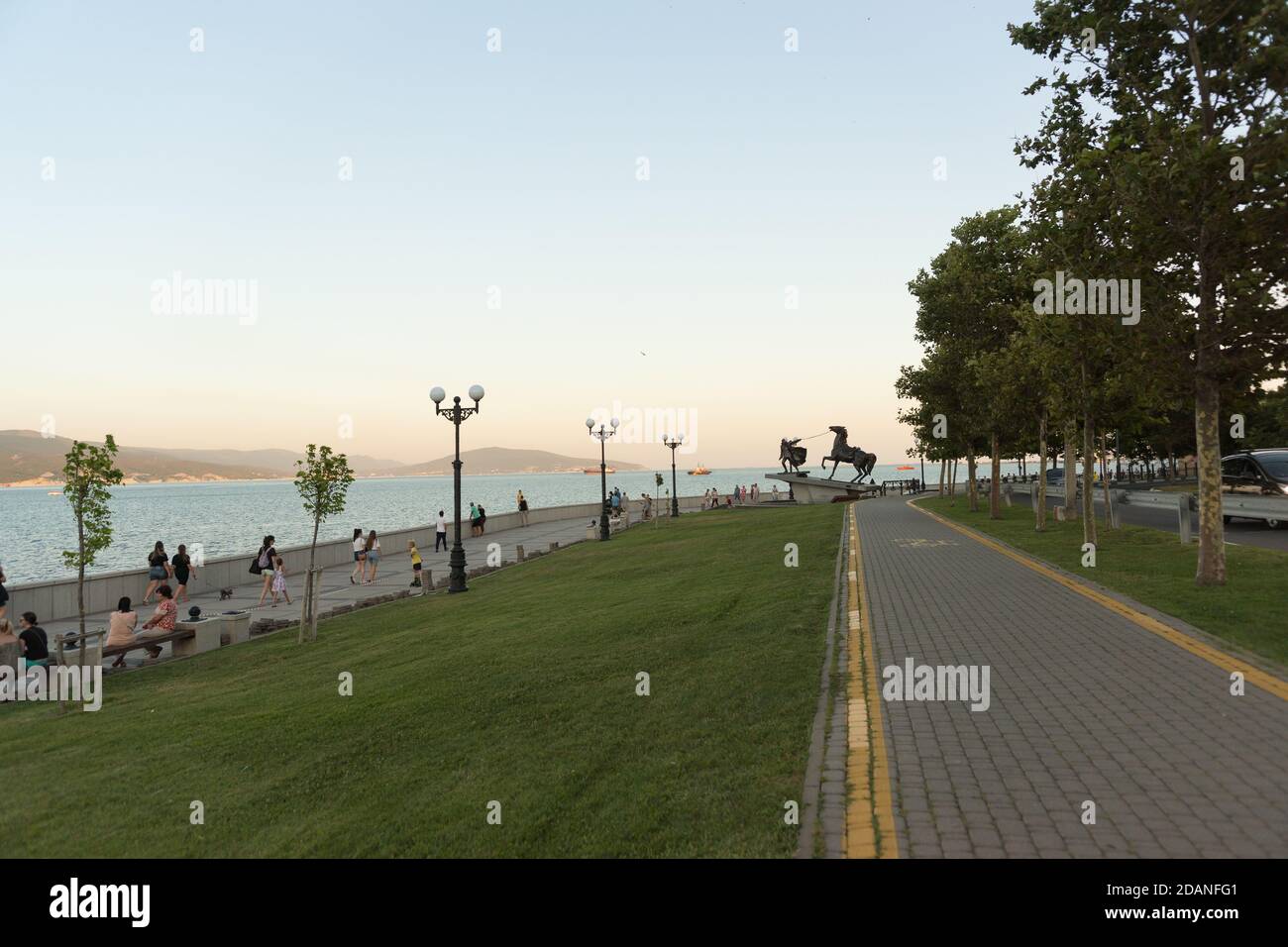Russia, Novorossiysk, July 11, 2020: Evening embankment of Admiral Serebryakov of the black sea city. Citizens and guests relax on the benches at suns Stock Photo