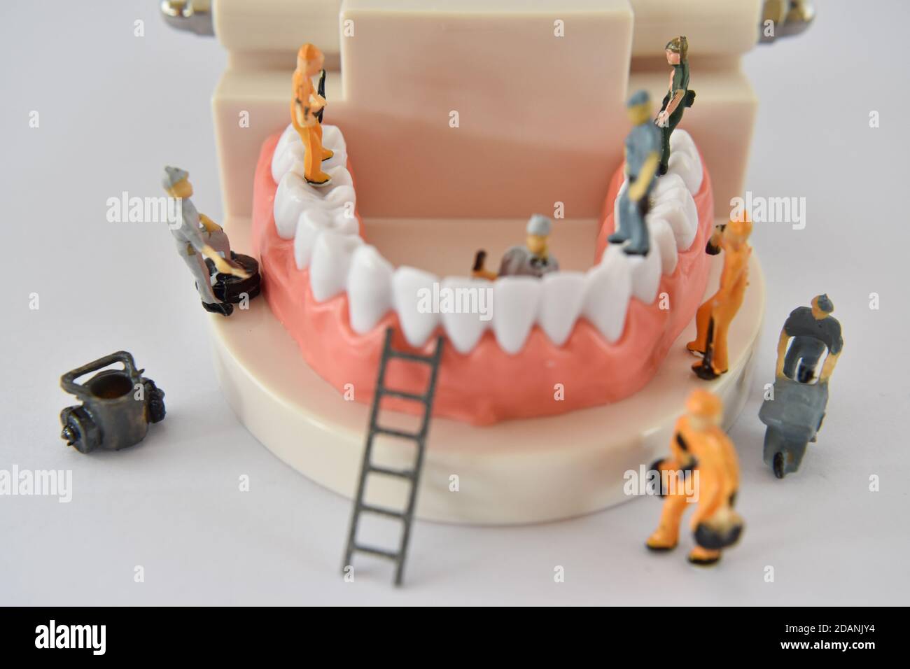 miniature people to repair a tooth or small figure worker cleaning tooth model as medical and healthcare. cleaning dental care or dentist concept. Stock Photo