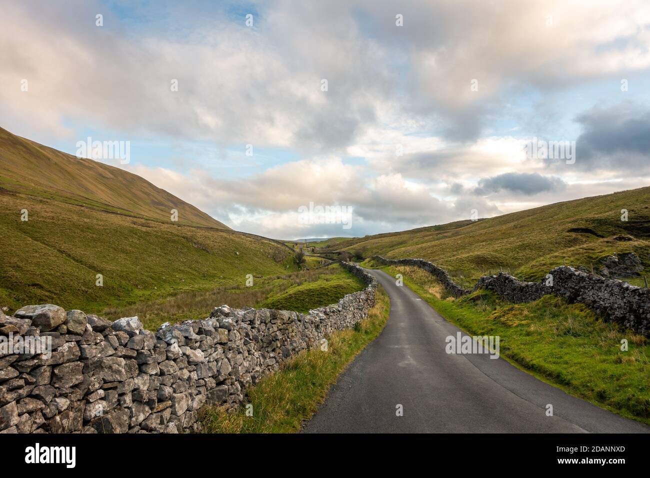 UK landscape: View looking north up the picturesque country lane of Barbondale Road, lined with drystone wall, Cumbria - Yorkshire Dales National Park Stock Photo