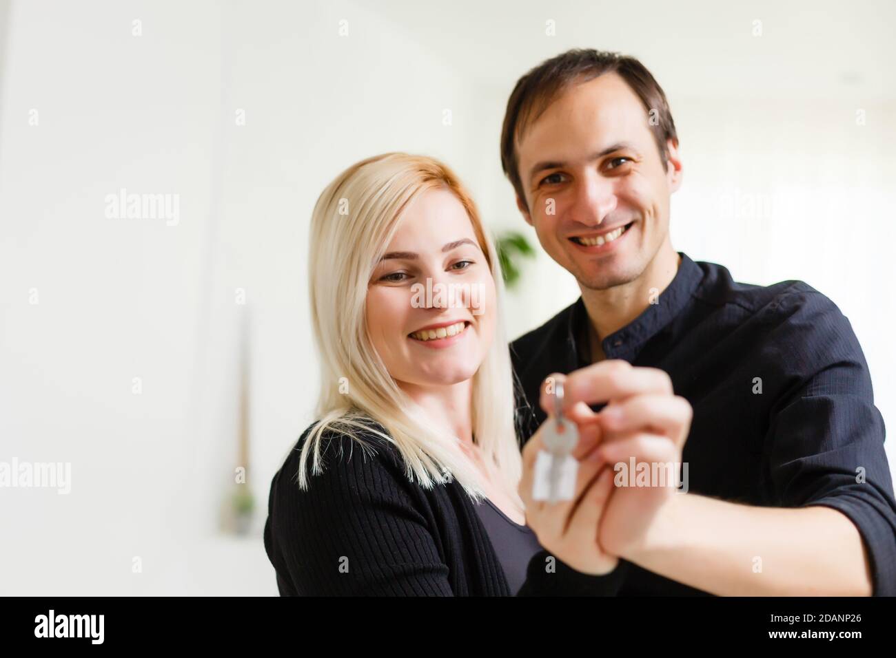 Happy smiling young couple showing a pair of keys of their new house ...