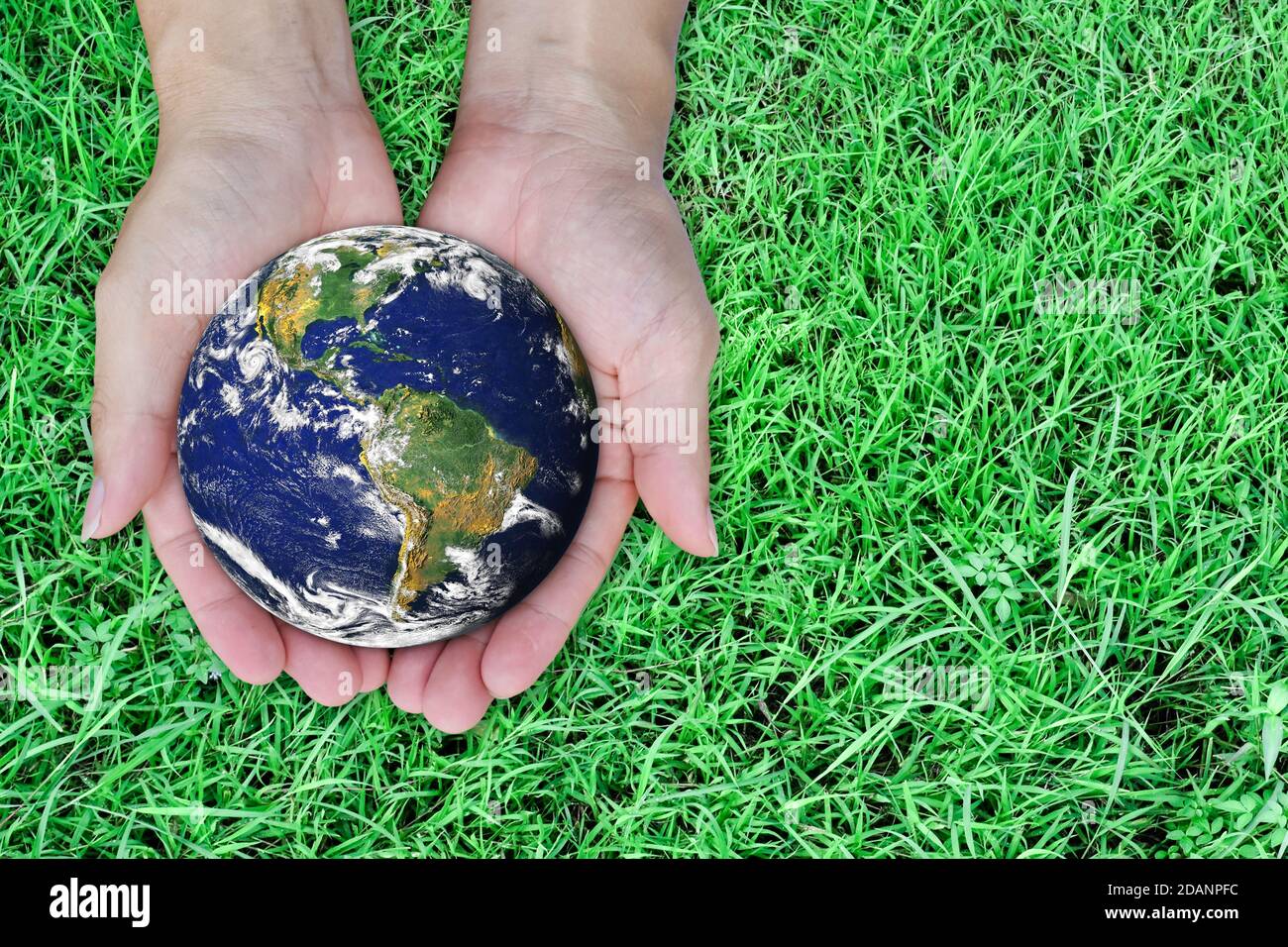 Earth day concept. Globe in hand on green lawn background. Elements of ...
