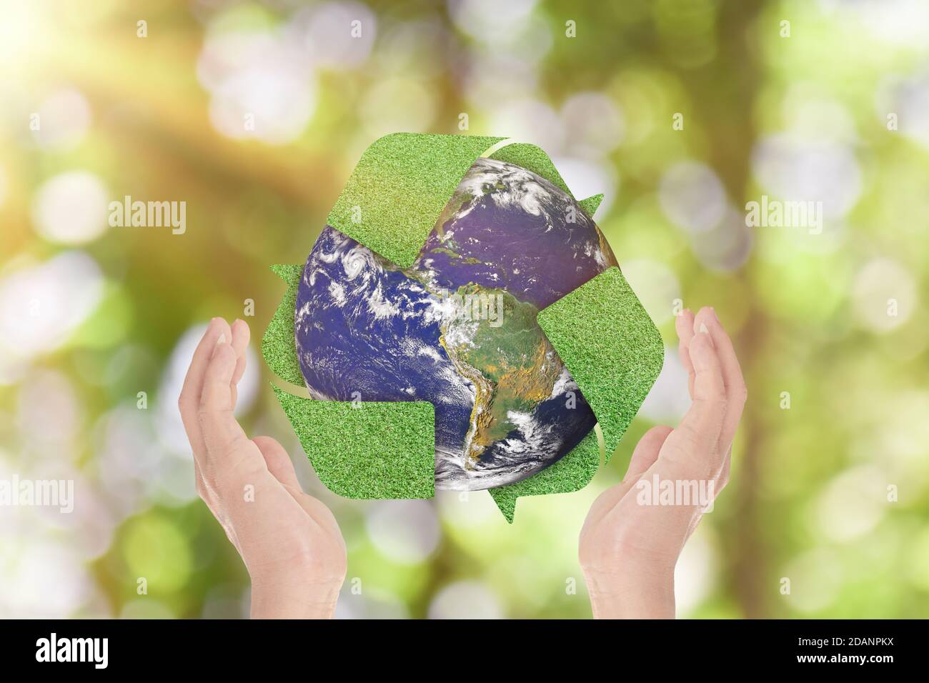 Green grass recycle symbol and Earth in hands over green nature background. Environment concept. Elements of this image furnished by NASA Stock Photo