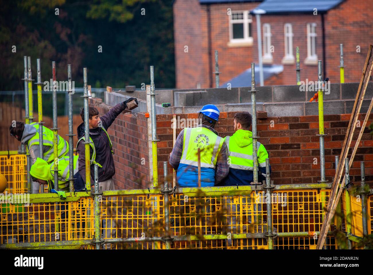 Apprentices trainee builders and brick layers being trained and supervised during the building and construction of new homes in the Cheshire countryside Stock Photo