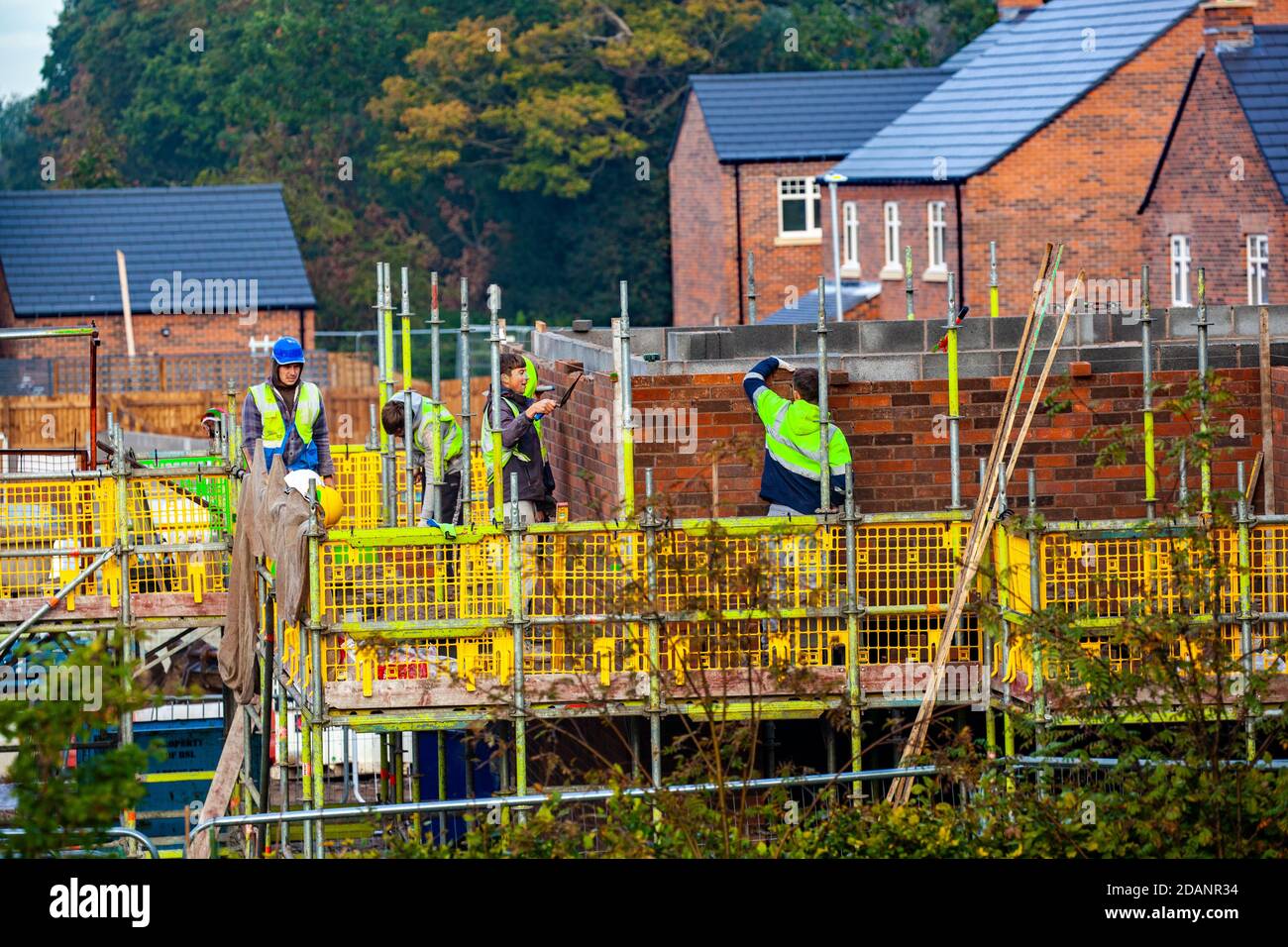 Apprentices trainee builders and brick layers being trained and supervised during the building and construction of new homes in the Cheshire countryside Stock Photo