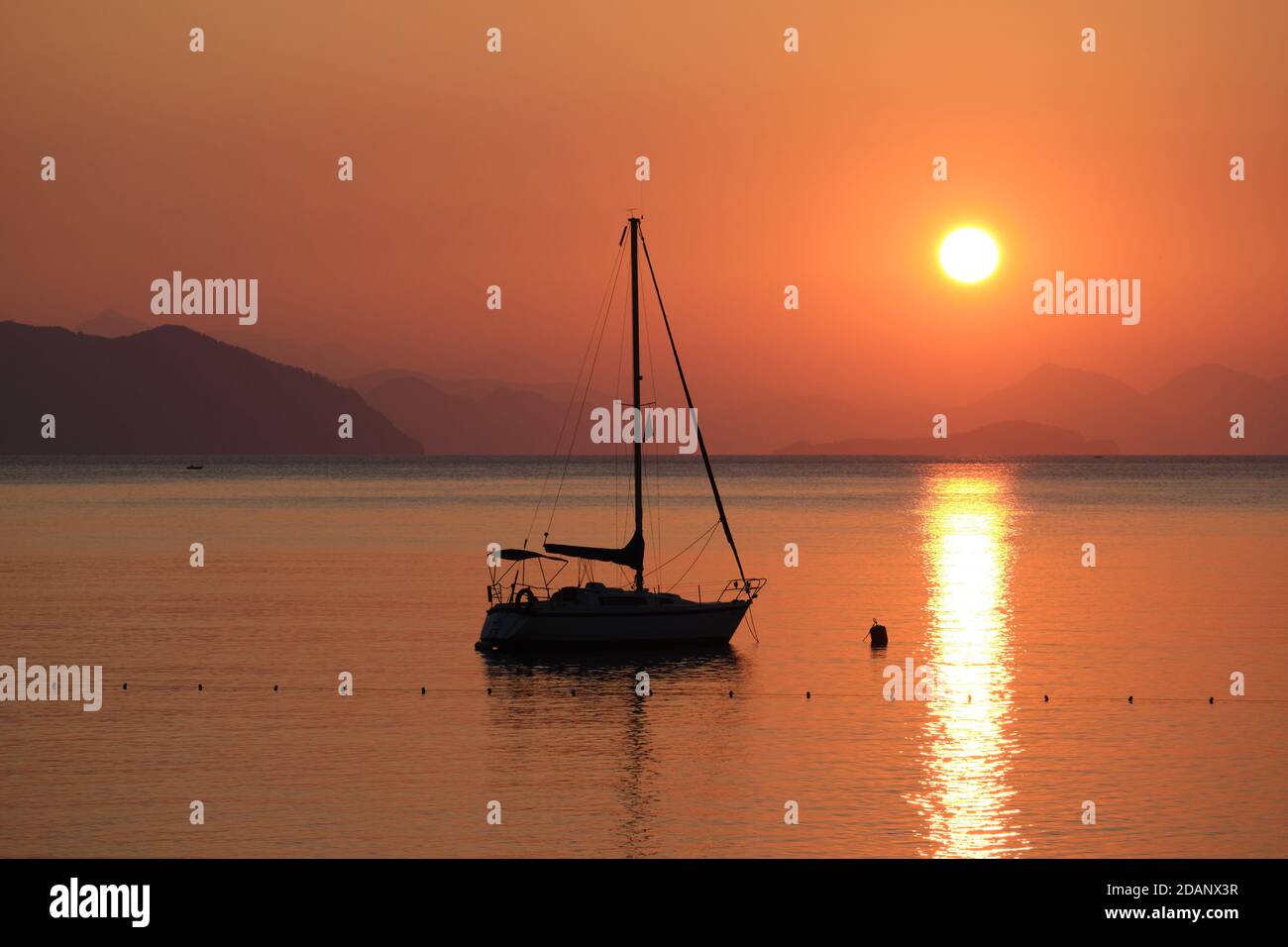 Beautiful sunrise in Aegean sea with boat and mountains, Turunc beach, Turkey Stock Photo