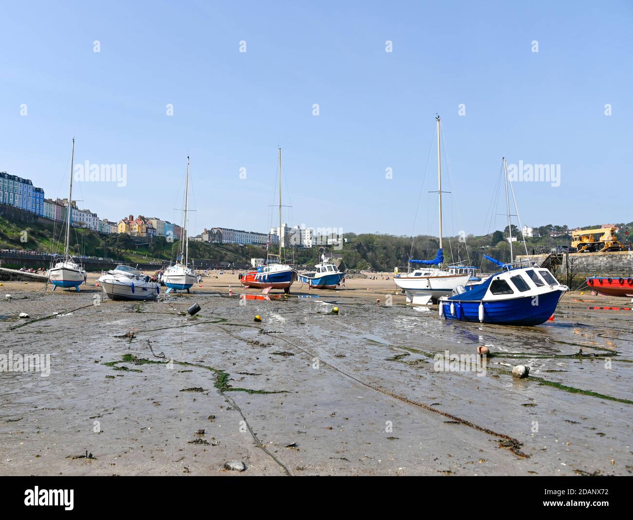 Tenby, Wales - April 15 2019 : The boats in the harbour at Tenby at low tide showing the mooring chains Stock Photo