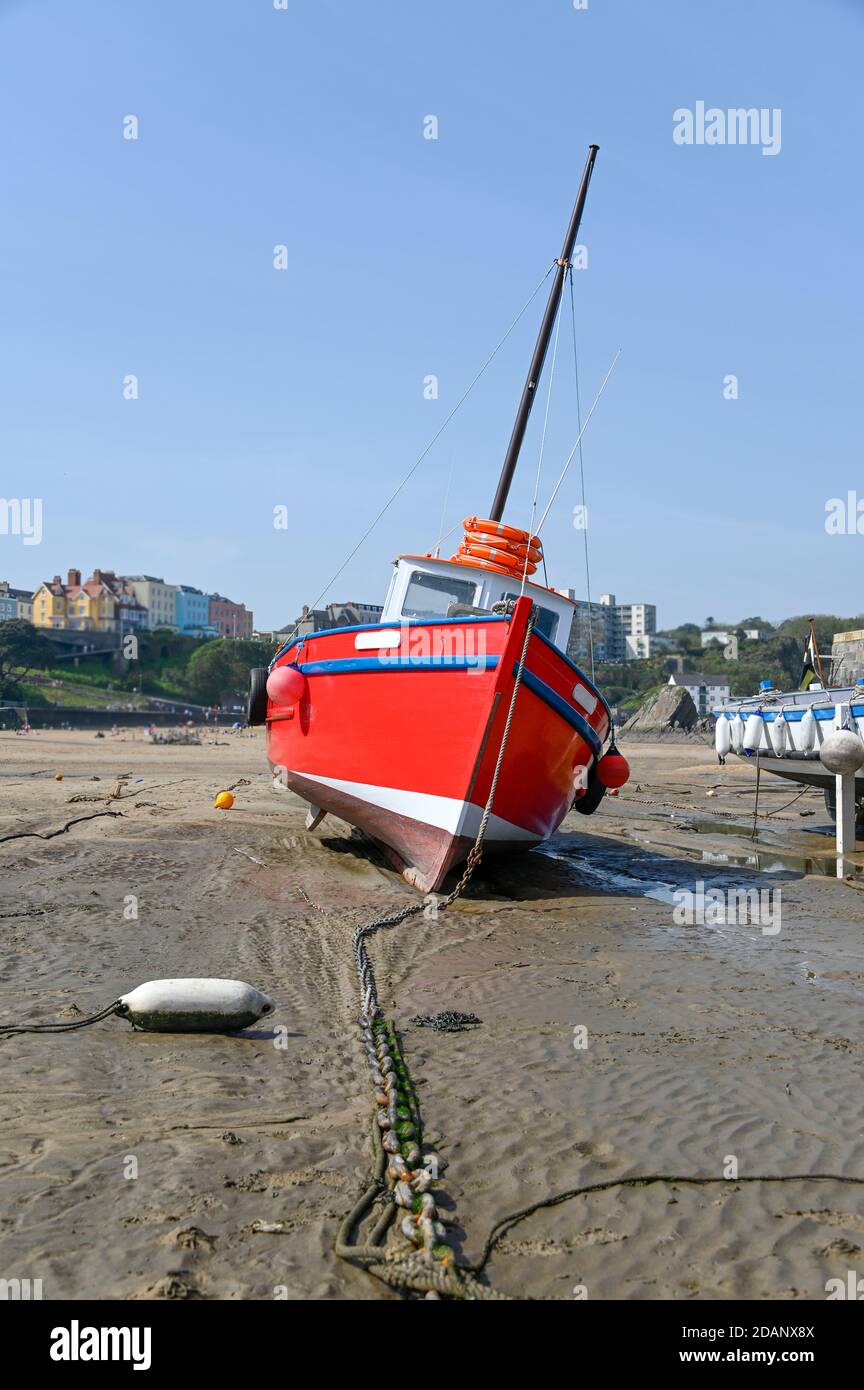 Red boat on the beach in Tenby harbour at low tide Stock Photo
