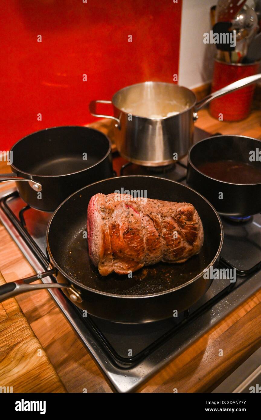 Roast beef joint home cooking for Sunday lunch UK - Searing the beef in frying pan before putting in oven   Photograph taken by Simon Dack Stock Photo