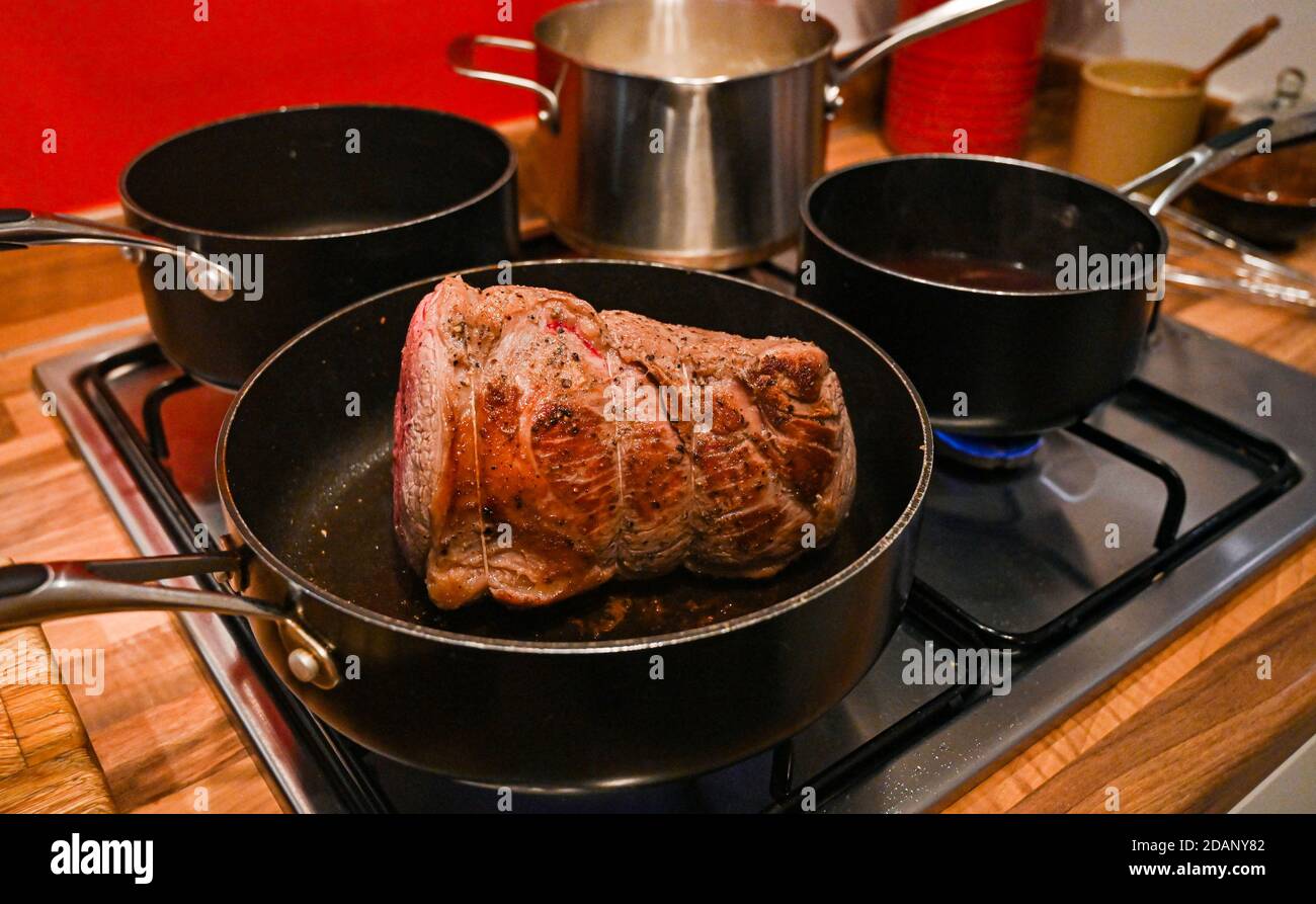 Roast beef joint home cooking for Sunday lunch UK - Searing the beef in frying pan before putting in oven   Photograph taken by Simon Dack Stock Photo