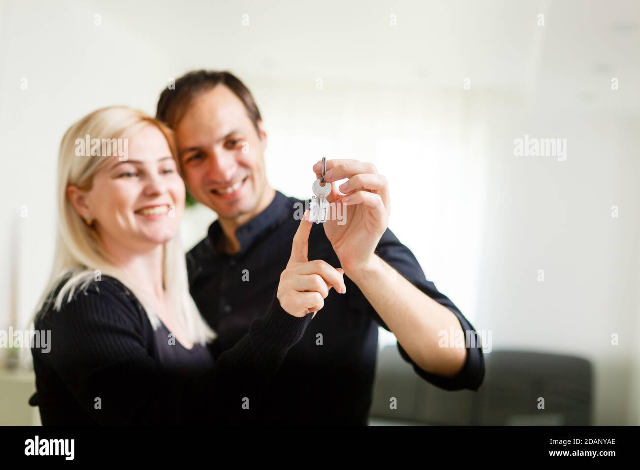 Happy smiling young couple showing a pair of keys of their new house ...