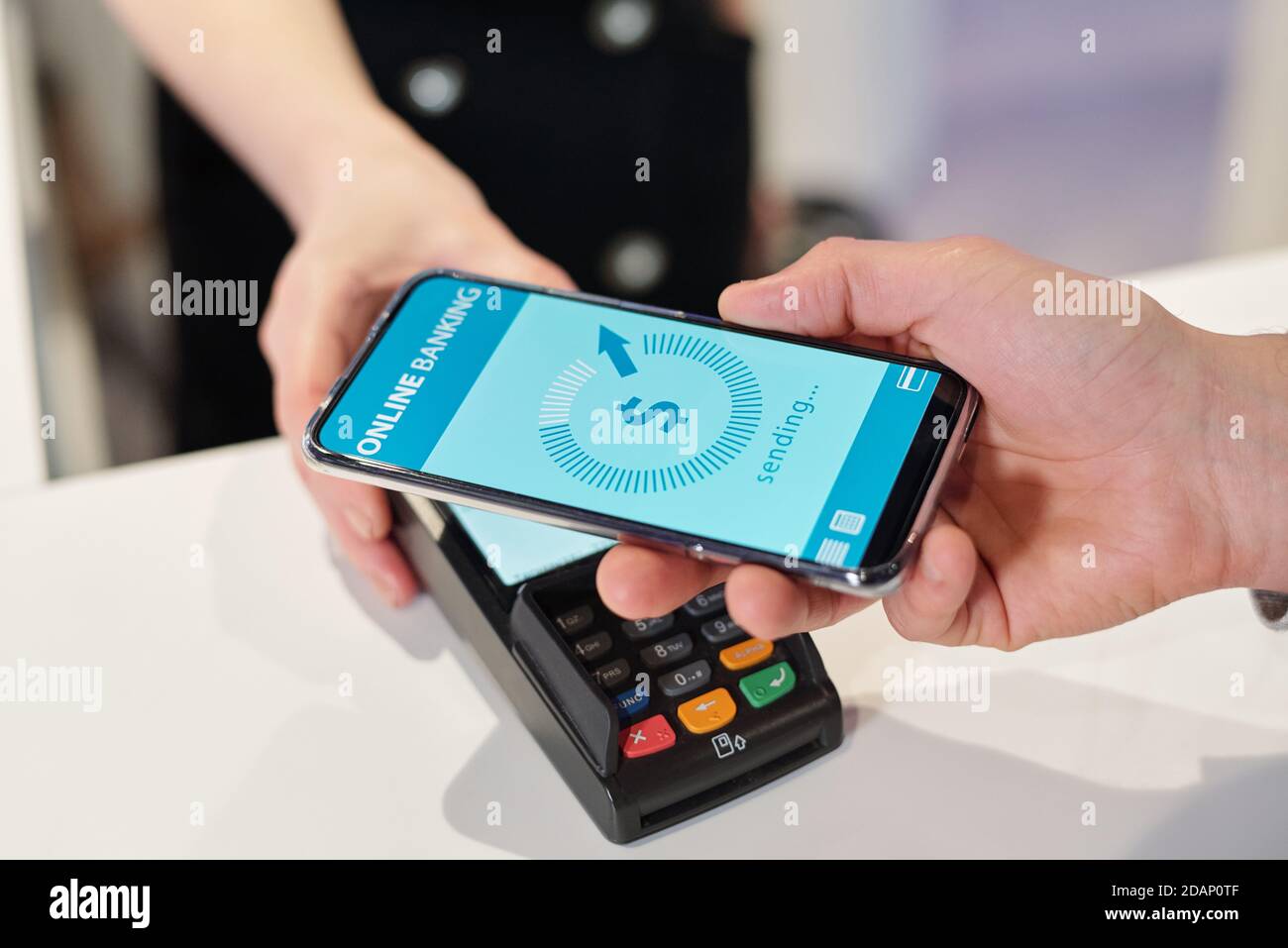 Hand of young man holding smartphone over terminal during contactless payment Stock Photo