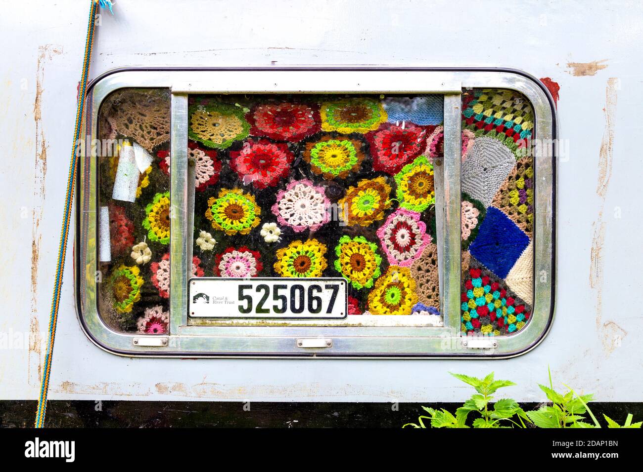 A houseboat window covered with crochet work along the Grand Union Canal, Colne, Valley, Uxbridge, UK Stock Photo