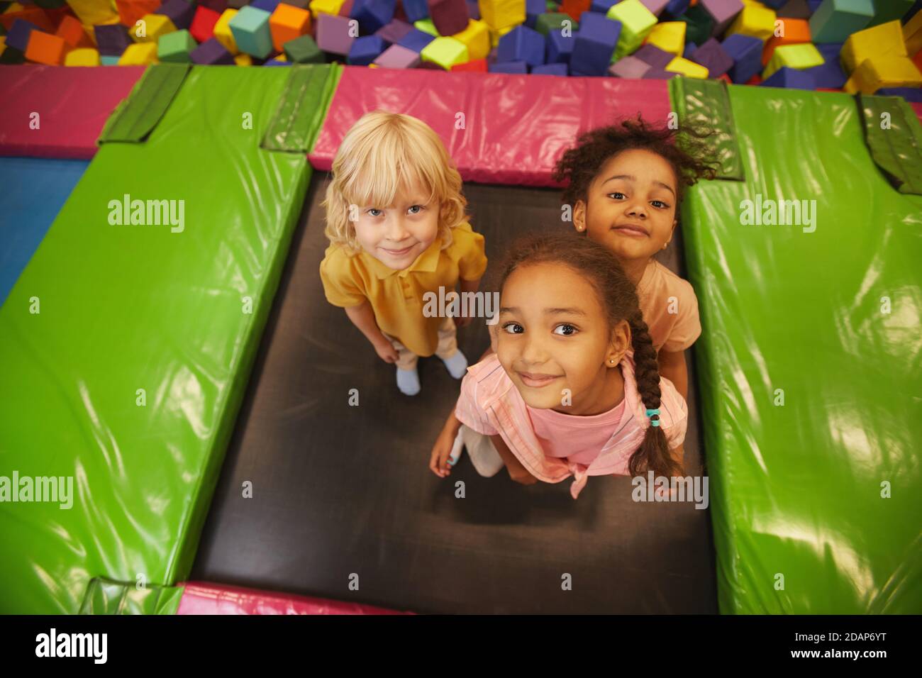Portrait of group of children looking at camera while jumping on trampoline in entertainment park Stock Photo