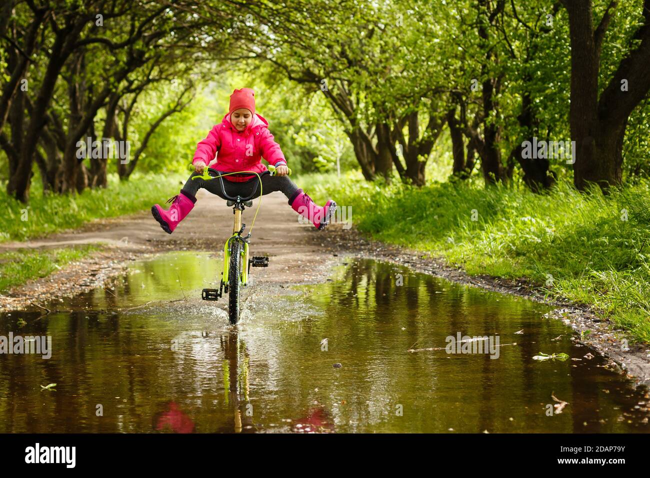 little girl riding bike in water puddle Stock Photo Alamy