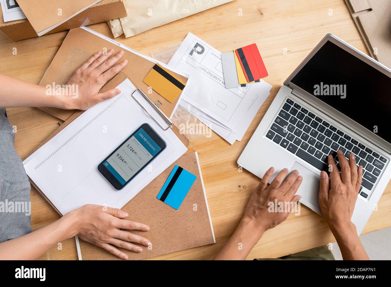 Hands of young managers using mobile gadgets while receiving online payments Stock Photo