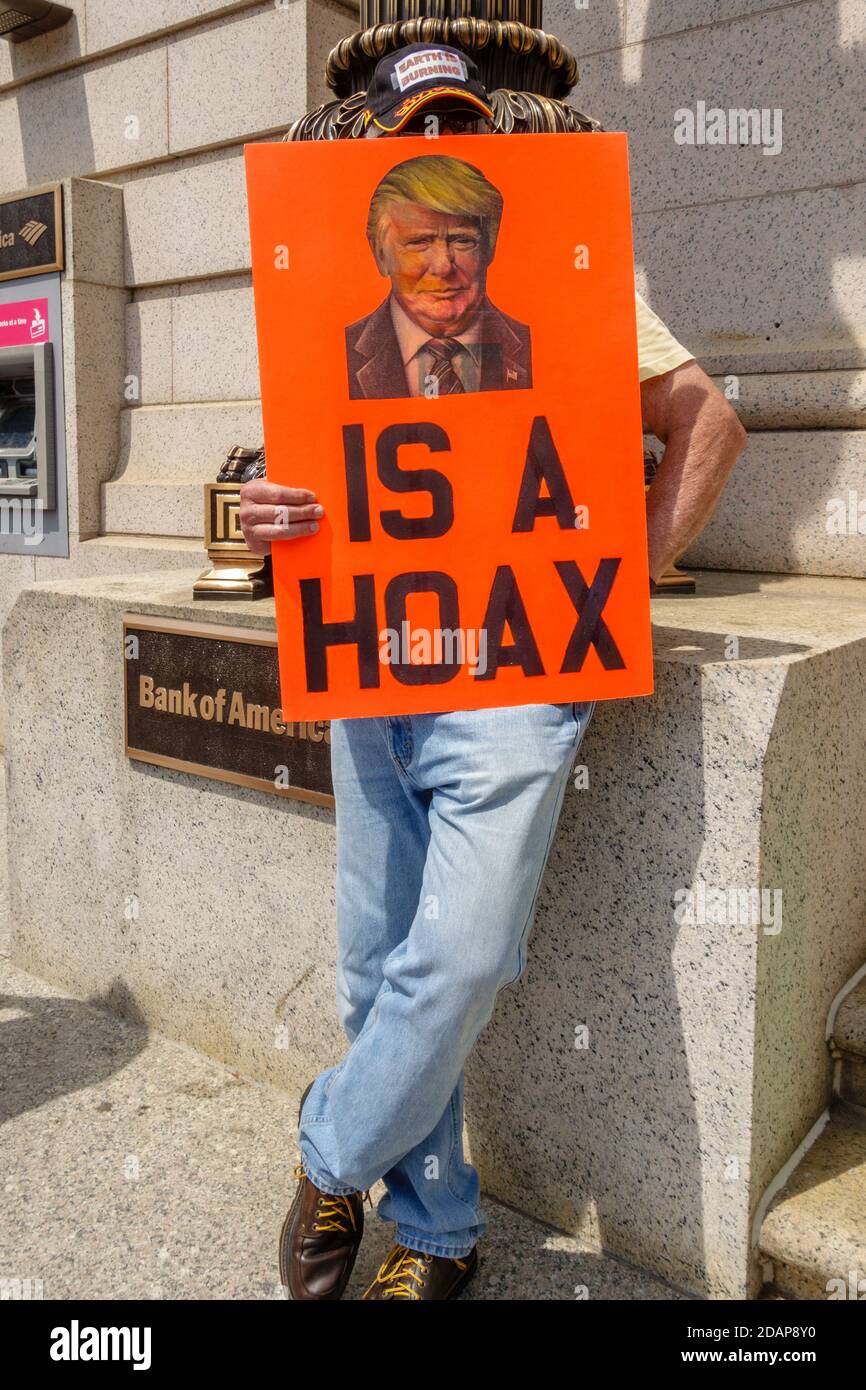 Protester holding sign with picture of Donald Trump reading 'Trump is a hoax' Stock Photo