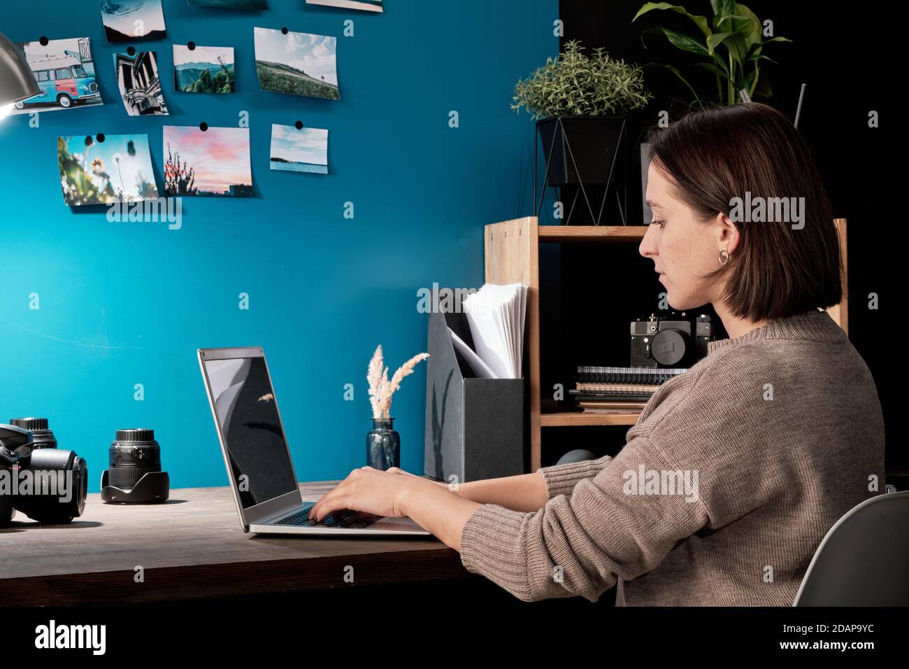 Contemporary young female designer or photographer using laptop in studio Stock Photo
