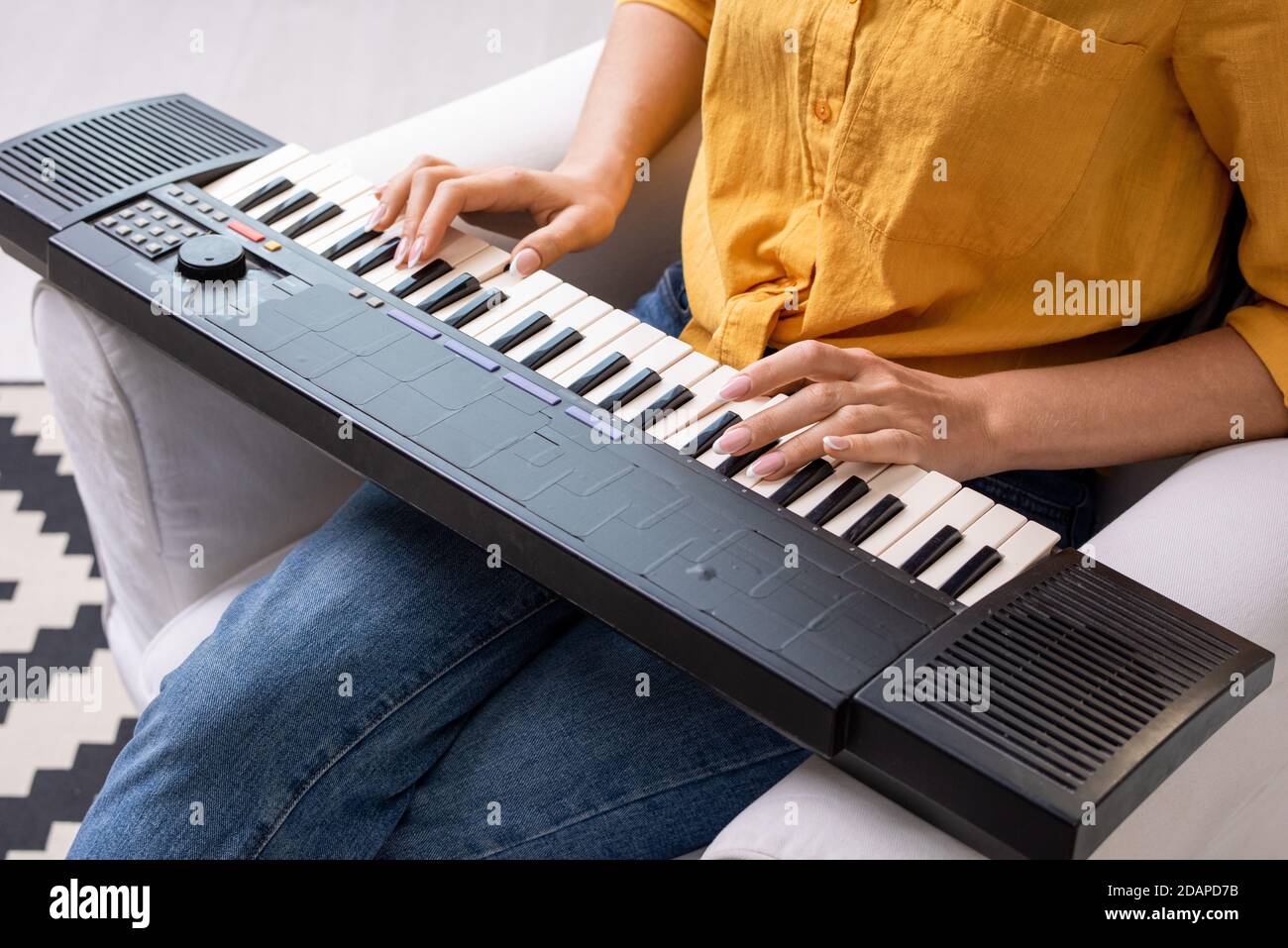 Hands of young woman in casualwear pressing keys of musical synthesizer keyboard Stock Photo