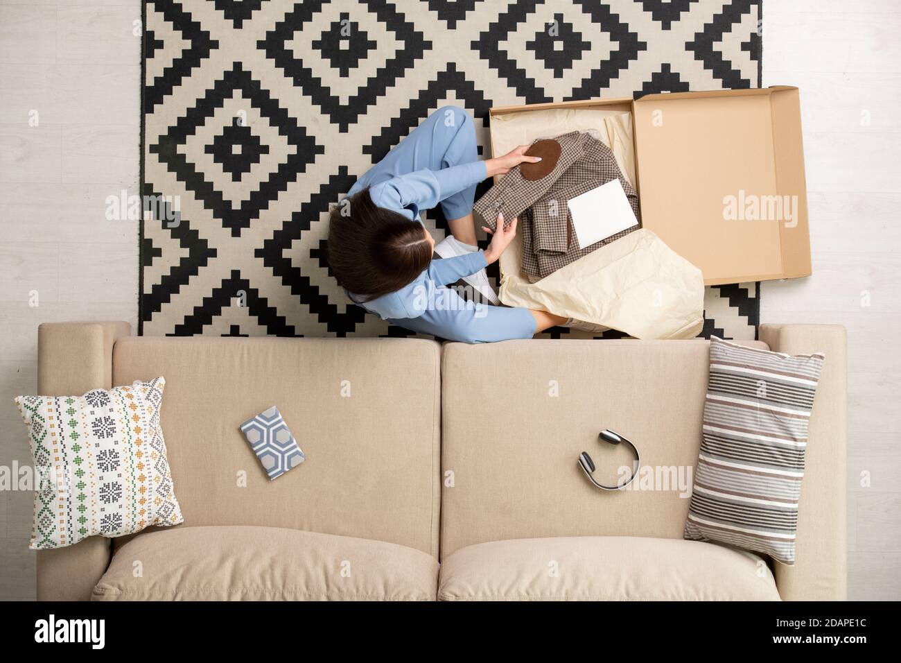 View of brunette girl looking at new folded checkered jacket from online shop Stock Photo