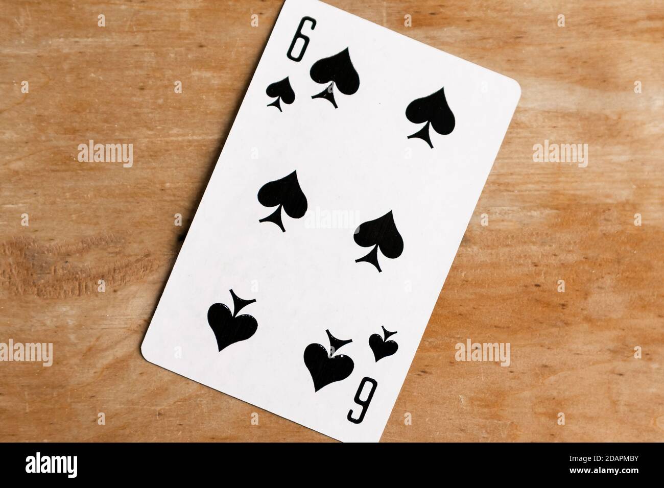 Six of Spades playing card, wooden background. Stock Photo