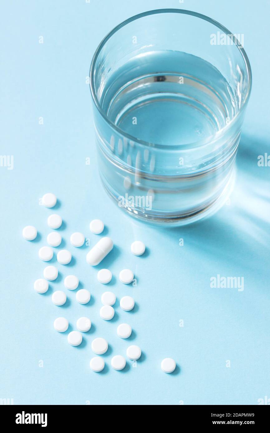 Pills, glass of water and packaging on a blue background. Selective focus. Stock Photo
