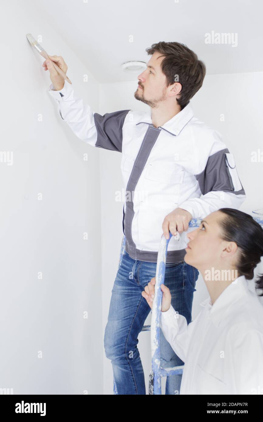 couple painting their new home holding a paint roller Stock Photo