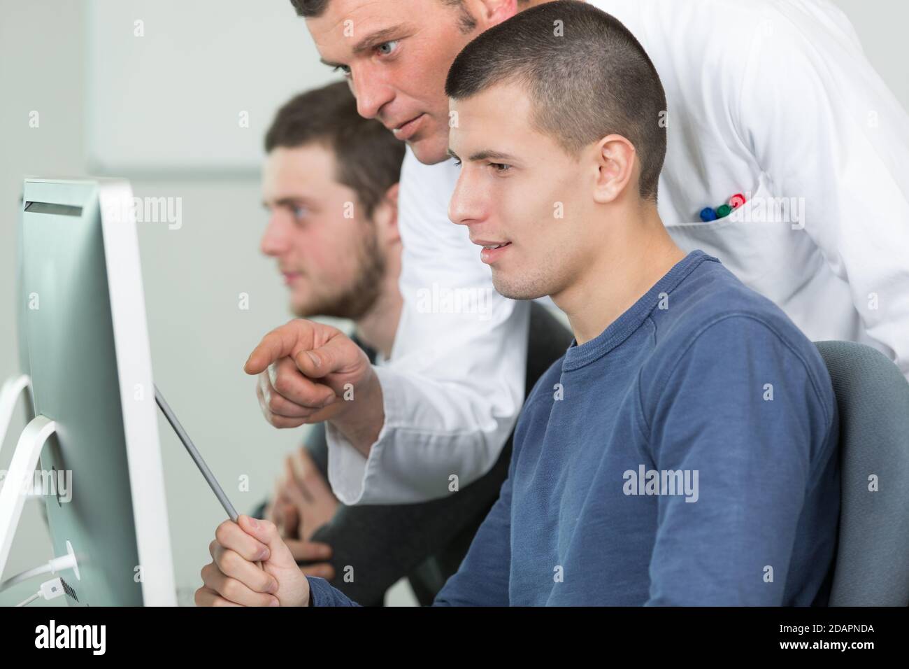 teacher with male students using computers Stock Photo - Alamy