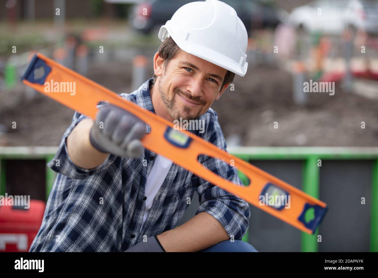 builder holding spirit level at construction site Stock Photo - Alamy