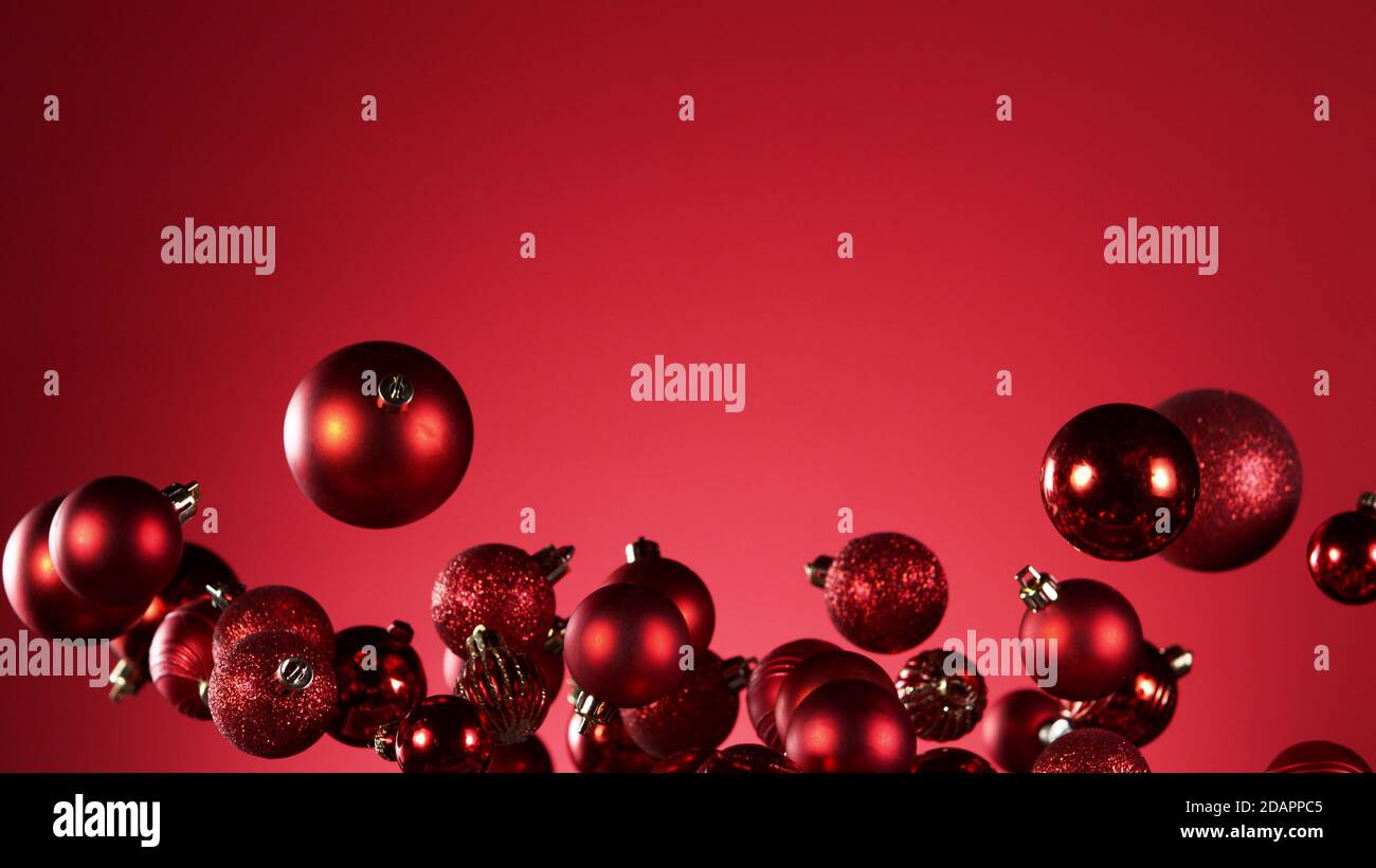 Flying christmas balls on coloured background, concept of celebrating, studio shot. Stock Photo