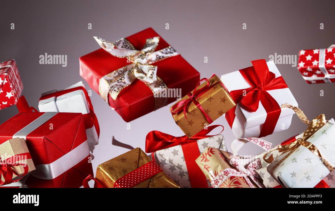 Flying christmas gifts on coloured background, concept of celebrating, studio shot. Stock Photo