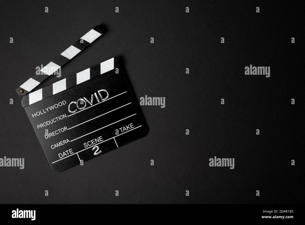 Horizontal color image with a overhead view of a movie clapperboard during the second wave of the coronavirus pandemic on a black background Covid con Stock Photo