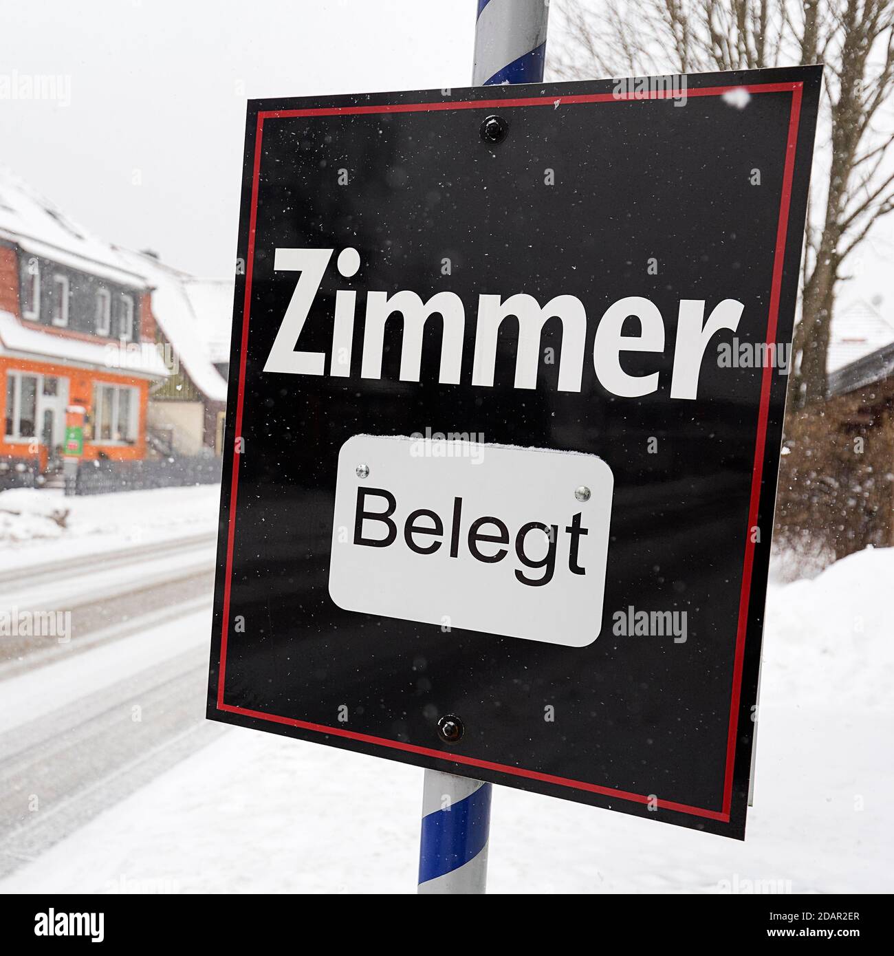 Black sign with the inscription Zimmer belegt, dreary winter weather, district Schierke, Wernigerode, Harz County, Saxony-Anhalt, Germany Stock Photo