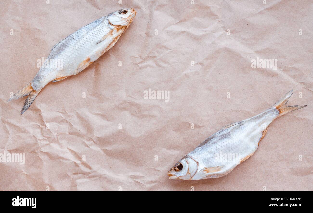 Dried fishes flat lay template banner on craft paper background with empty space for text. Horizontal salted roach cover backdrop. Seafood snack poster, flyer design. Fish frame promotion shop. Stock Photo