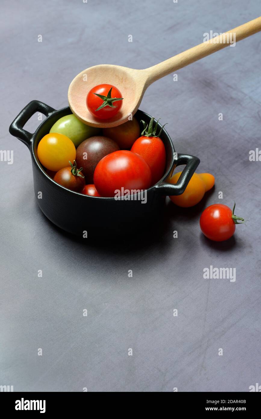 Different cherry tomatoes in pot with cooking spoon, Germany Stock Photo