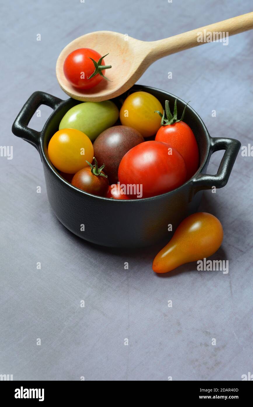 Different cherry tomatoes in pot with cooking spoon, Germany Stock Photo