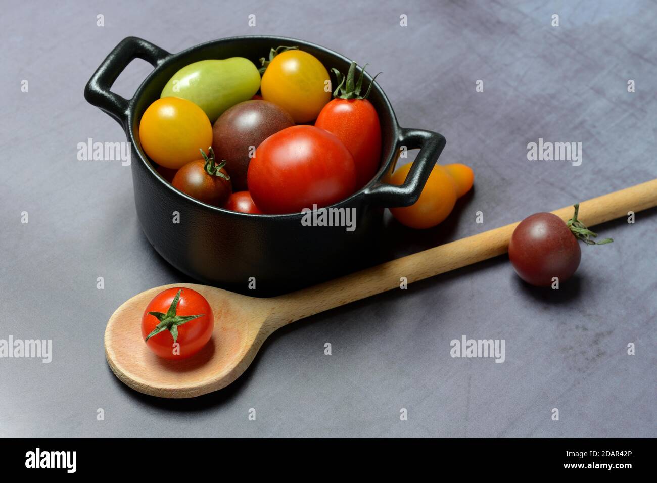 Different cherry tomatoes in pot with cooking spoon, Germany Stock Photo