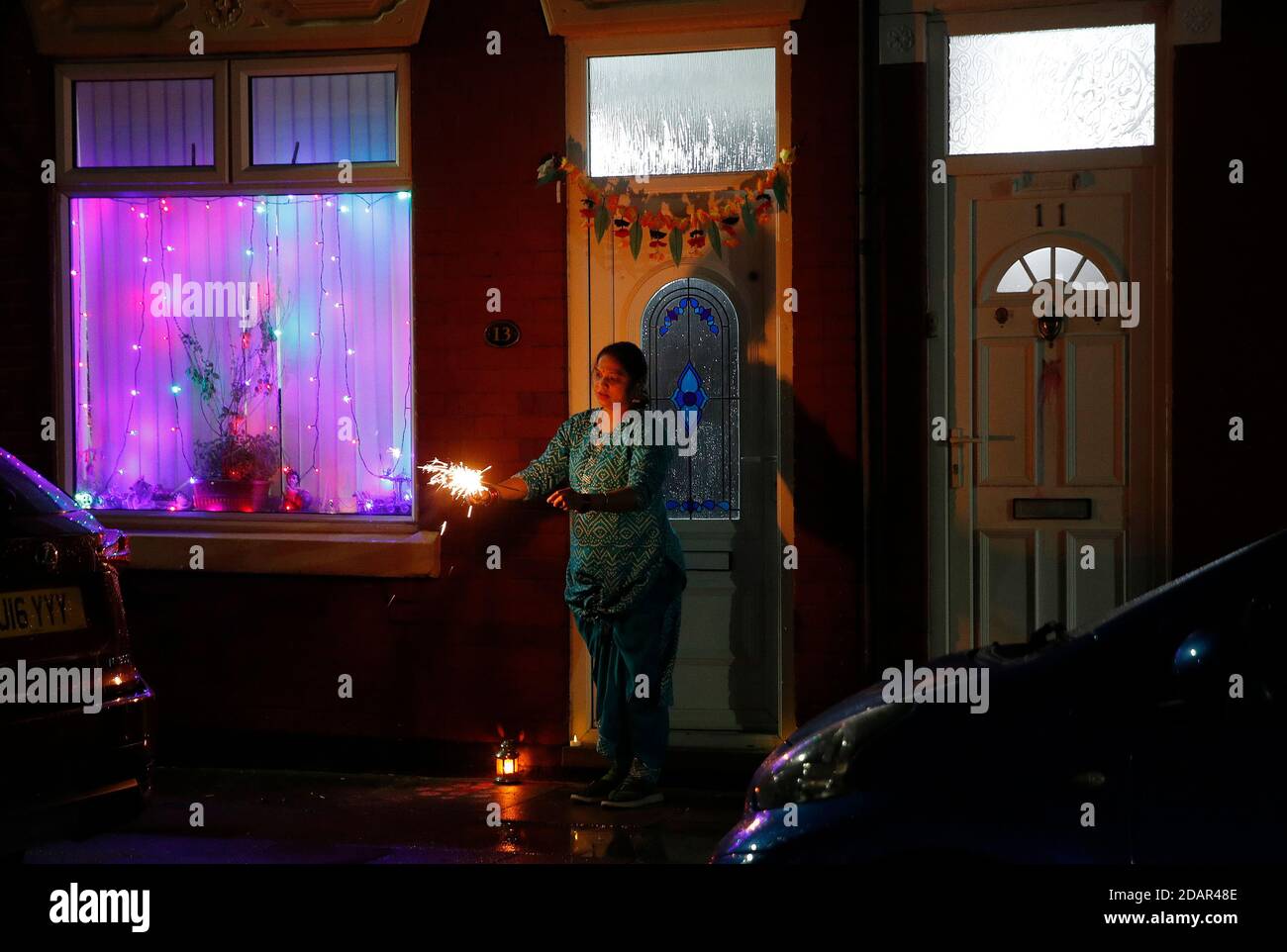 Leicester, Leicestershire, UK. 14th November 2020. A woman lights sparklers on her doorstep after Covid-19 restrictions meant the usual Diwali day ceremony and celebrations were cancelled this year. Credit Darren Staples/Alamy Live News. Stock Photo