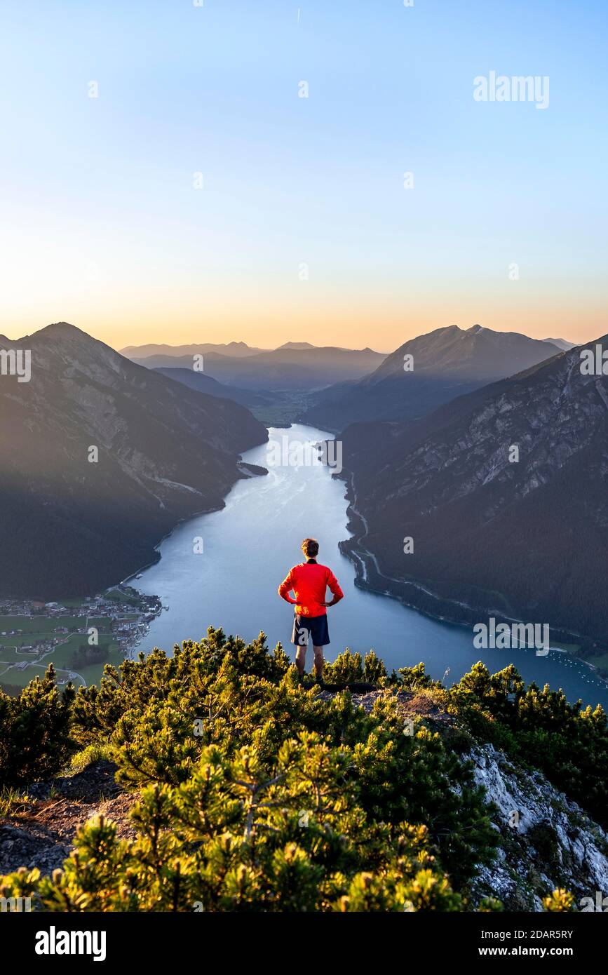 Sunset, young man looking over mountain landscape, view from the top of Baerenkopf to the Achensee, on the left Seebergspitze and Seekarspitze Stock Photo