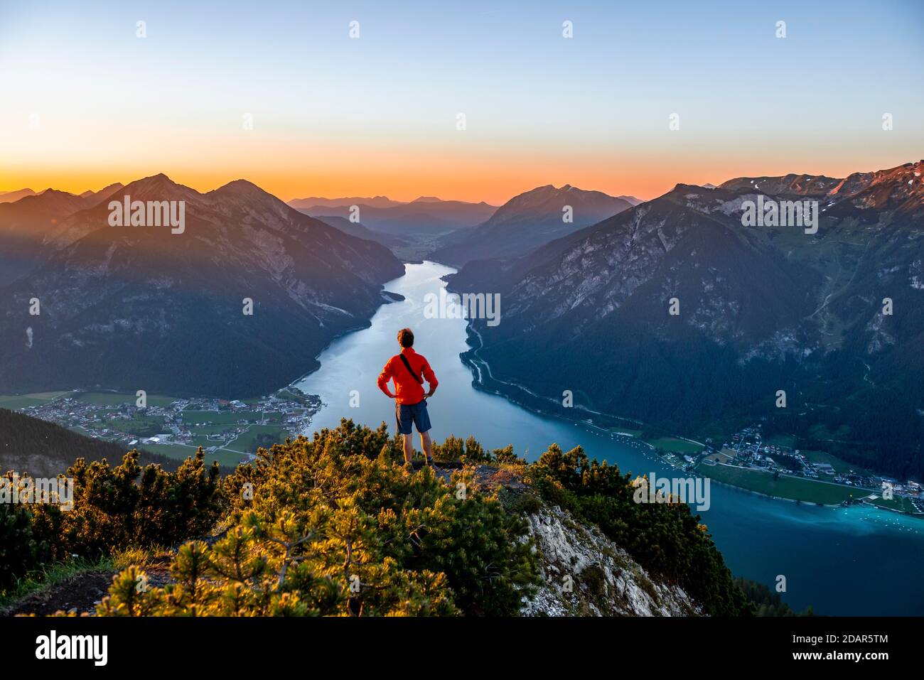 Sunset, young man looking over mountain landscape, view from the top of the Baerenkopf to the Achensee, left Seebergspitze and Seekarspitze, right Stock Photo