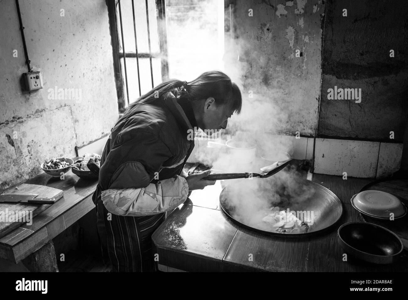 Woman cooking in a farmhouse in Ping'An in Zhangjiajie National Forest Park, China Stock Photo